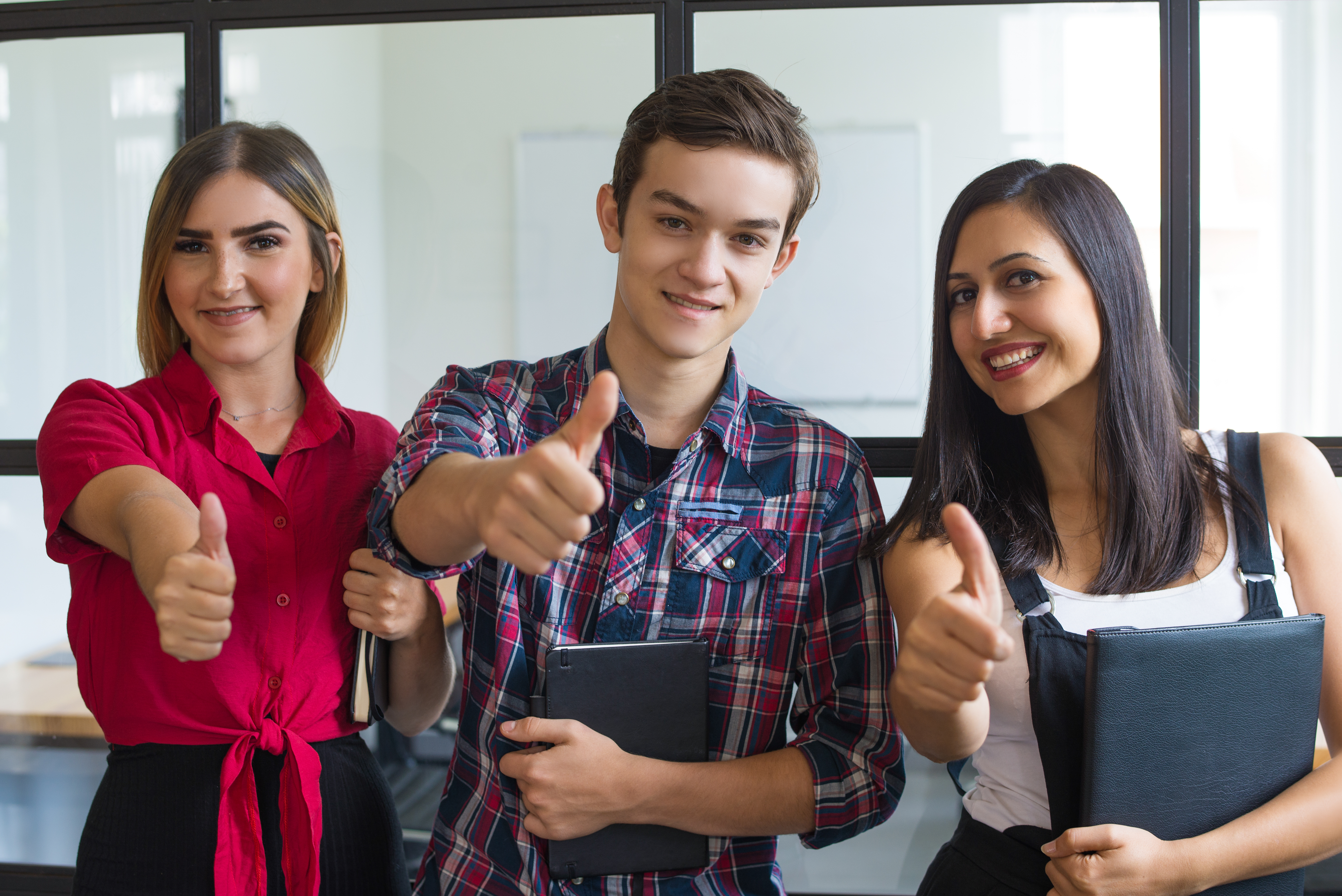 Portrait of successful young students showing thumbs up tirocinio